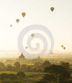 Sunrise and hot air balloons fly over misty Bagan, Myanmar