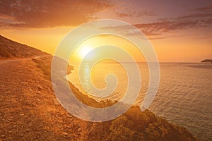 Sunrise on the island of Crete near Spinalonga with sea coast, rocks and dirt road