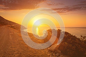 Sunrise on the island of Crete near Spinalonga with sea coast, rocks and dirt road