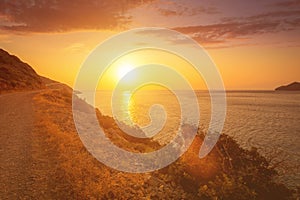 Sunrise on the island of Crete near Spinalonga with sea coast, rocks and dirt road