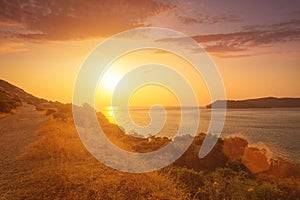 Sunrise on the island of Crete near Spinalonga with sea coast, rocks and dirt road