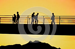 A sunrise with the Iztaccihuatl volcano and pedestrians on a bridge photo
