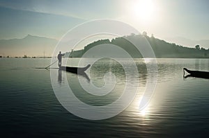 Sunrise on lake,fisherman rowing the boat
