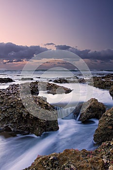 Sunrise landscape of ocean with waves clouds and rocks