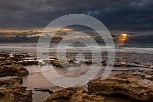 Sunrise landscape of ocean with waves clouds and rocks