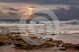 Sunrise landscape of ocean with waves clouds and rocks