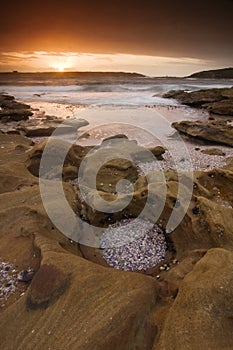 Sunrise landscape of ocean with waves clouds and rocks