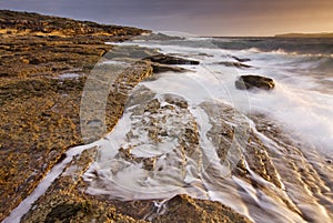 Sunrise landscape of ocean with waves clouds and rocks