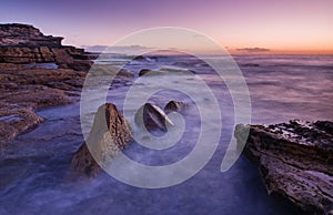 Sunrise landscape of ocean with waves clouds and rocks