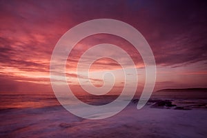 Sunrise landscape of ocean with waves clouds and rocks