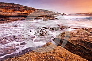 Sunrise landscape of ocean with waves clouds and rocks