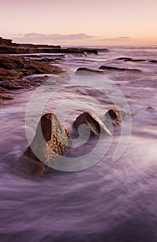 Sunrise landscape of ocean with waves clouds and rocks