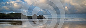 Sunrise landscape panorama Three Cliffs Bay in Wales with dramatic sky