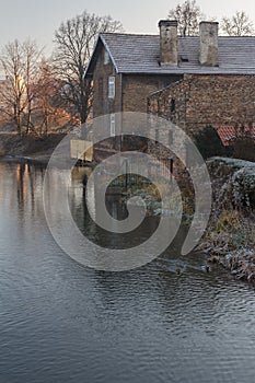 Sunrise landscape with riverbank and brick old house
