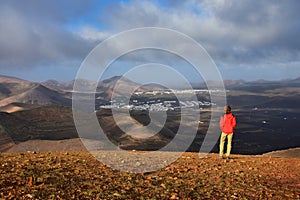 Sunrise in Lanzarote. A woman standing on a mountain, looking to the small towns Yaiza and Uga, surrounded by volcanic landscape.