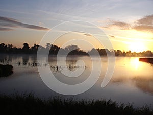 The sunrise made the water glisten and the birds began to fly over the water peacefully .