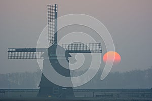 Sunrise misty winter morning with windmill
