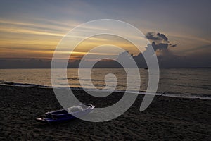 Sunrise in the morning with one boat on beach and one boat in the sea