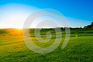 Sunrise in mountains landscape. Green grass meadow at sunset