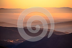 Sunrise in mountains, shape of hills in morning mist, white edit space