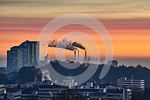 Sunrise in Munich, Germany. Sunrise in the city with a beautiful park in the foreground and smoking industrial chimneys in the