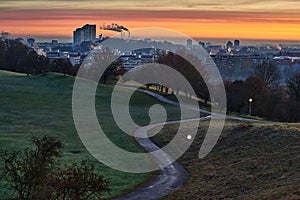 Sunrise in Munich, Germany. Sunrise in the city with a beautiful park in the foreground and smoking industrial chimneys in the