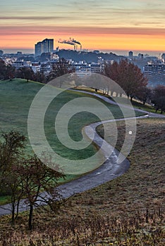 Sunrise in Munich, Germany. Sunrise in the city with a beautiful park in the foreground and smoking industrial chimneys in the