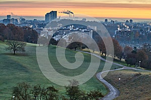 Sunrise in Munich, Germany. Sunrise in the city with a beautiful park in the foreground and smoking industrial chimneys in the