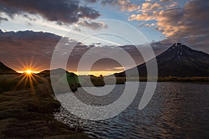 Sunrise next to volcano Mount Taranaki and lake in the forground