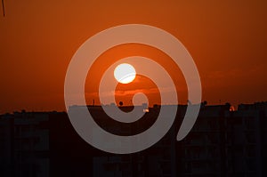 Sunrise orange coloured sky Sun clouds. Buildings silhouette photography black Crane machinary. Construction site foreground.