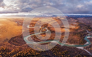 Sunrise over the autumn steppe with the river against the background of mountains