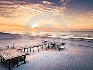 Sunrise over the beach and wooden dock aerial view