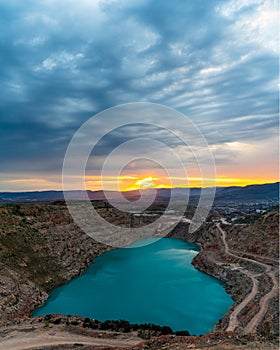 Sunrise over the blue quarry lake in the shape of a heart. Limestone fluxing of Kadykovo quarry, Balaklava, Crimea. A