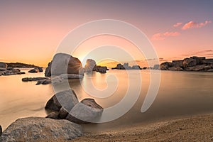 Sunrise over boulders and beach on Cavallo Island in Corsica