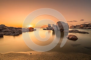 Sunrise over boulders and beach on Cavallo Island in Corsica