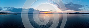 Sunrise over calm ocean aerial panorama. Sunset orange and blue color cloudy sky. Chalkidiki, Greece