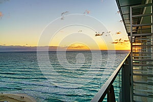 Sunrise over Cancun's coastline viewed from an architectural balcony, highlighting a peaceful ocean with gentle