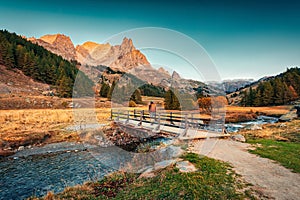 Sunrise over Claree valley and male tourist walking through wooden bridge in autumn at French Alps, France