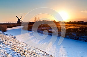 Sunrise over Dutch windmill and frozen canal