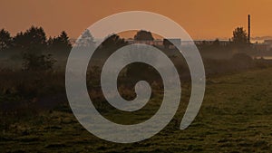 Sunrise over the field, fog creeps along the ground and dissipates, lighting mode, time lapse.