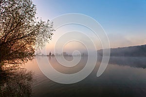 Sunrise over foggy lake. Canes on foreground on the lake coast