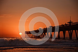 Sunrise over horizon and fishing pier.