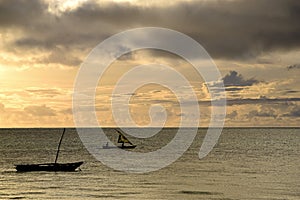Sunrise over the Indian Ocean. Sailboat under yellow, cloudy sky