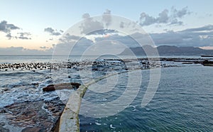 Sunrise over jetty seawall at Dale Brook Tidal Swim Pool in Cape Town South Africa SA