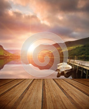 Sunrise over lake with boats moored at jetty with wooden planks