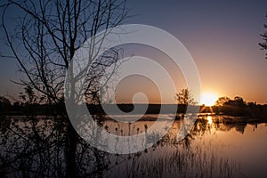 Sunrise over lake in the spring, landscape in penumbra, reflection photo