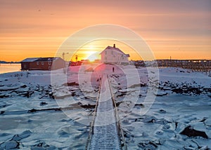 Sunrise over nordic house and wooden bridge on coastline in winter at Lofoten Islands