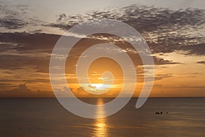 Sunrise over ocean with fishing boat with golden sky