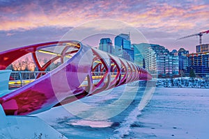 Sunrise over Peace Bridge in Calgary with frozen ice and snow-covered Bow River in Winter