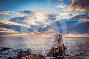 Sunrise over a rocky beach. Colorful clouds reflecting in the sea